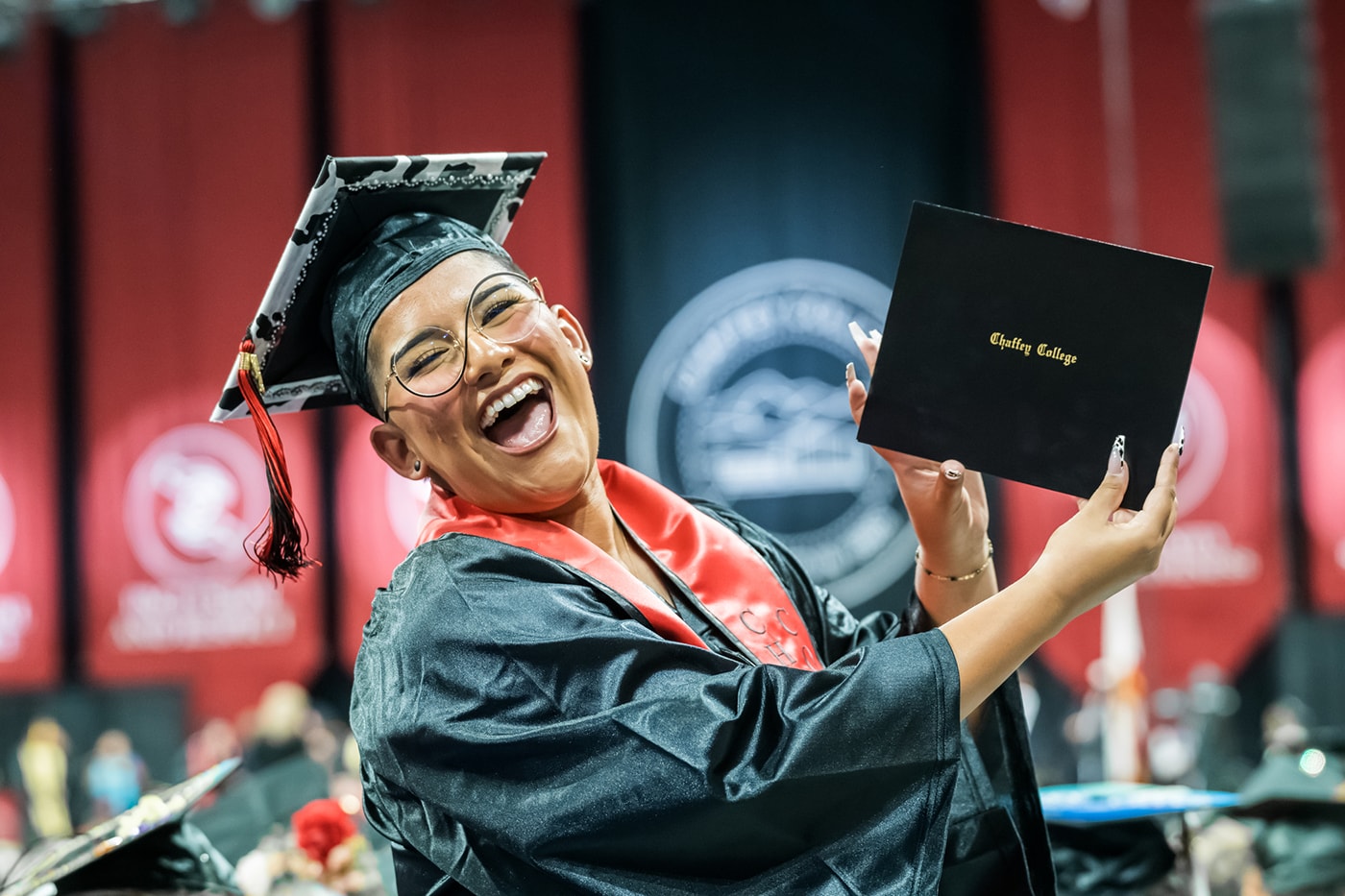 Graduate holding their diploma and smiling, filled with joy and excitement.